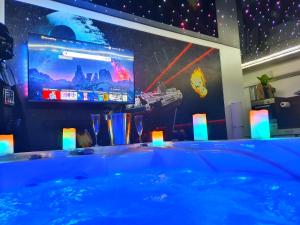 a room with a tub with a tv and a large screen at -GALAXY SPA-JACUZZI-INSOLITE-4PERS-Jardin-SPA-CLIM in Holtzwihr