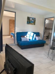 a living room with a blue couch and a tv at LES GÎTES DE BIBINE gîtes tout confort coin calme et tranquille in Rabi
