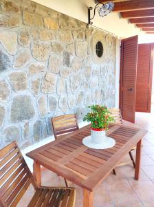 a wooden table with two chairs and a stone wall at Holiday home Mennulita in Lipari
