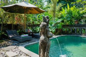 a statue of a bear with an umbrella next to a pool at Villa JJ and Spa Ubud in Ubud