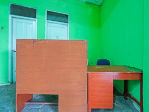 Habitación verde con escritorio de madera y pared verde. en SPOT ON 91325 Pondok Hijau Guest House Syariah, en Cilimus 2