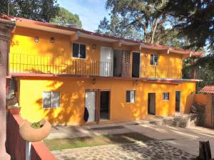 a yellow house with a balcony on a street at Hotel Villas Monteli Suites Cuernavaca in Cuernavaca