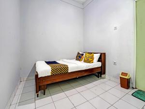 a small bed in a room with white walls at SPOT ON 91325 Pondok Hijau Guest House Syariah in Cilimus 2