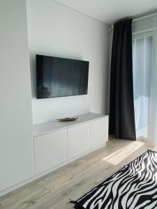 a white entertainment center with a television on a wall at Mano jūra 2 apartamentai in Palanga