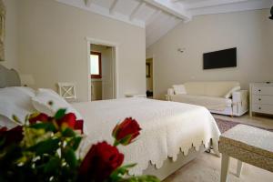 a white bedroom with a bed and a couch at Corte dei Mirti, camere signorili in Iglesias