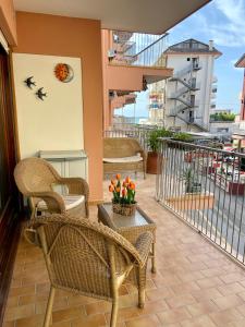 a balcony with wicker chairs and a table with flowers at Le terrazze vista mare in Lido di Jesolo