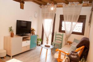 ein Wohnzimmer mit einem TV und einem Tisch in der Unterkunft LA CASITA DEL PORTAL in Pedro Bernardo