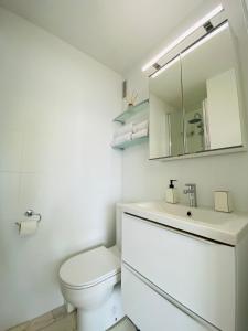 a white bathroom with a toilet and a mirror at L'instant présent - Petite vue mer in Villers-sur-Mer