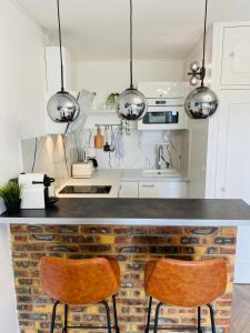 a kitchen with a counter with two chairs at it at L'instant présent - Petite vue mer in Villers-sur-Mer