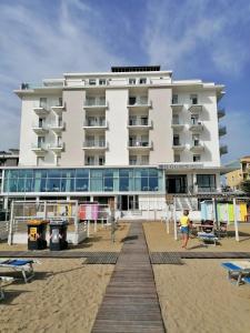 a large white building on the beach next to a building at Hotel Globus in Bellaria-Igea Marina