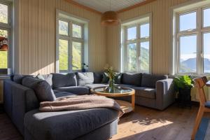 a living room with couches and a table and windows at Feriehus med flott havutsikt ved Hauklandstranden in Leknes