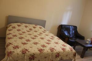 a bedroom with a bed with a flowered blanket and a chair at Iren Apartment in Batumi