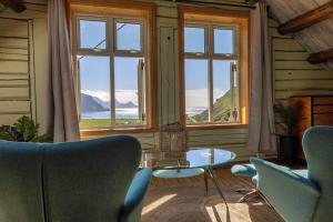 a room with chairs and a table and windows at Feriehus med flott havutsikt ved Hauklandstranden in Leknes