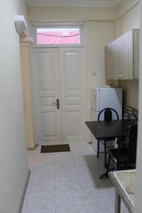 a kitchen with a white door and a table and a refrigerator at Iren Apartment in Batumi