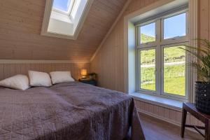 a bedroom with a bed and two windows at Feriehus med flott havutsikt ved Hauklandstranden in Leknes