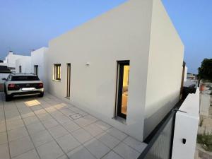 una casa blanca con un coche aparcado al lado en Samoqueira 12, en Porto Covo