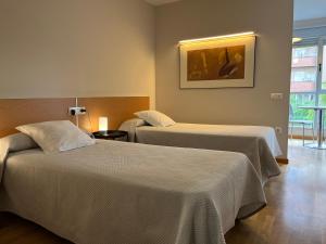 Habitación de hotel con 2 camas y una foto en la pared en Apartamentos León, en León