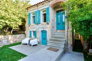 ein Haus mit blauen Türen und zwei weißen Stühlen in der Unterkunft MINIQ HOMES 102 - Historical Stone House with Garden Cinema in Foça