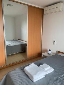 ein Schlafzimmer mit einem Spiegel und einem Bett mit Handtüchern in der Unterkunft Aroeira Beach House in Aroeira