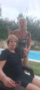 zwei Frauen auf einem Stuhl neben einem Pool in der Unterkunft Residence les Jasmins in Sousse