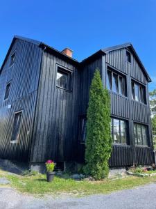 ein schwarzes Haus mit einem Baum davor in der Unterkunft Villa Lyckan in Söråker