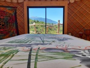sypialnia z łóżkiem i widokiem na okno w obiekcie Yourte contemporaine avec magnifique vue sur les montagnes w mieście Rigarda