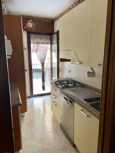 uma cozinha com armários brancos e um forno com placa de fogão em Le terrazze vista mare em Lido di Jesolo