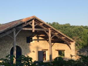 a stone house with a wooden roof with trees at Roc du Lapin in Sainte-Colombe-de-Villeneuve