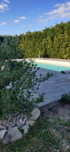a swimming pool next to a landscaping with a tree at L'Arche d' Engel in Courpière
