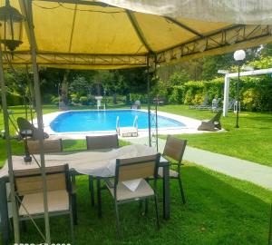 een tafel en stoelen onder een gele parasol bij een zwembad bij Casa Rustica Neiro in Santiago de Compostela