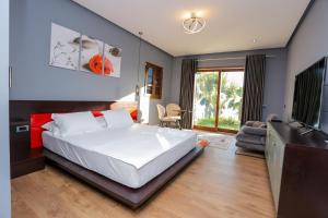 een slaapkamer met een groot wit bed en een televisie bij Villa Kristiano 21 in Sarandë