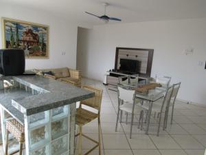 a living room with a table and chairs and a television at Luz do Sol Pinheira in Pinheiro