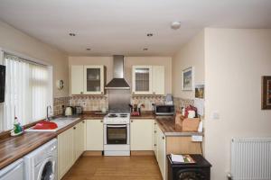 Una cocina con gabinetes blancos y un horno de estufa. en Gower Bungalow Mumbles, en Mumbles