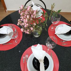 una mesa negra con platos rojos, vasos y flores en Casa de charme no clima de Pedra Azul, en Domingos Martins