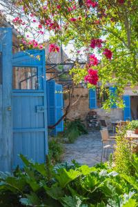 Sa Casa Rotja في سينيو: باب أزرق مفتوح في حديقة بها زهور وردية