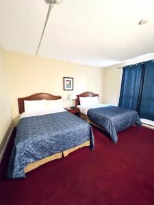 a hotel room with two beds and a red carpet at Fairway Inn by the Falls in Niagara Falls +21 photos
