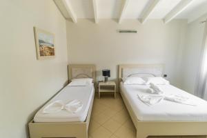 Dos camas en una habitación con paredes blancas. en Nikaj Premium Apart-Hotel, en Vlorë