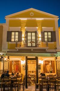 a group of people sitting at tables in front of a building at Ialemos Group in Symi