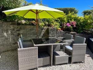 uma mesa e cadeiras com um guarda-sol amarelo em Camellia Cottage em Camborne