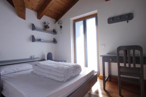 a bedroom with a bed with white sheets and a desk at LA PULCE INNEVATA - Dolomiti Affitti in Passo Rolle