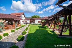 a yard with grass and wooden pavilions and buildings at Casa Belvedere Pietrosu in Moisei
