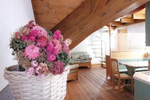 a basket full of pink flowers in a living room at LA PULCE INNEVATA - Dolomiti Affitti in Passo Rolle