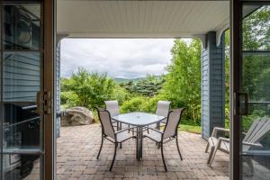 a patio with a table and chairs with a view at Le Boisé (Les Manoirs) Mont-Tremblant in Mont-Tremblant