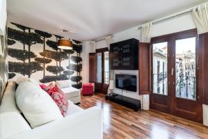 a living room with a white couch and a tv at Precioso apartamento en el centro de Granada in Granada