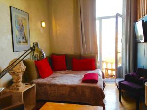 a room with a bed with red pillows and a television at appartement Monaco Beausoleil in Beausoleil