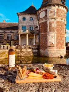 a plate of food and a bottle of wine and a building at Guest-House Château de Longecourt en Plaine in Longecourt-en-Plaine