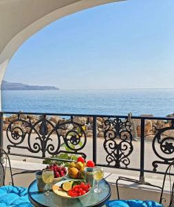 a table with fruits and vegetables on a balcony with the ocean at Apartmets Flisvos in Kalyves
