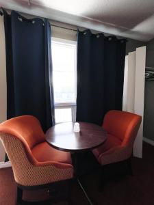 een kamer met 2 stoelen, een tafel en een raam bij Fairway Inn by the Falls in Niagara Falls