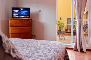 Schlafzimmer mit einem Bett und einer Kommode mit einem TV in der Unterkunft Colorful family condo with terrace and free parking in Guanajuato