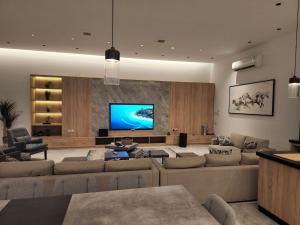 ein Wohnzimmer mit einem großen Sofa und einem Flachbild-TV in der Unterkunft شاليه فاخر جداً جداً وخاص in Riad